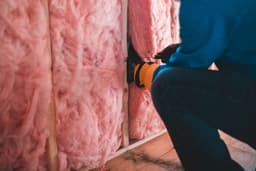 Mineral-wool insulation being fitted between wall studs
