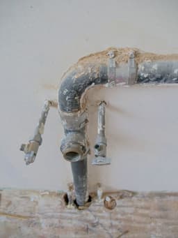 Older supply pipework and isolation valves exposed during a repair