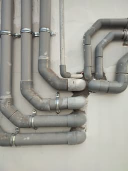 Plastic water and drainage pipes clipped to a wall during installation