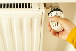 A hand setting a thermostatic radiator valve