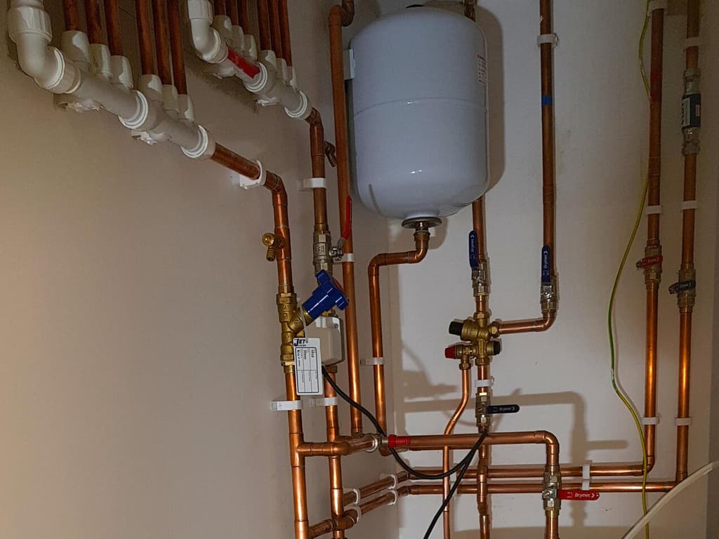 Precisely routed copper pipework around a domestic hot-water cylinder