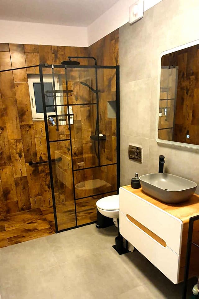 Finished bathroom with black-framed shower and timber tile