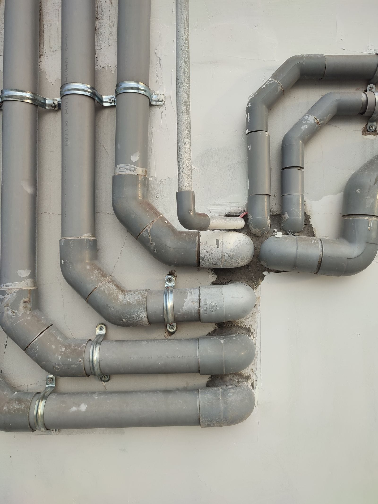 Plastic water and drainage pipes clipped to a wall during installation