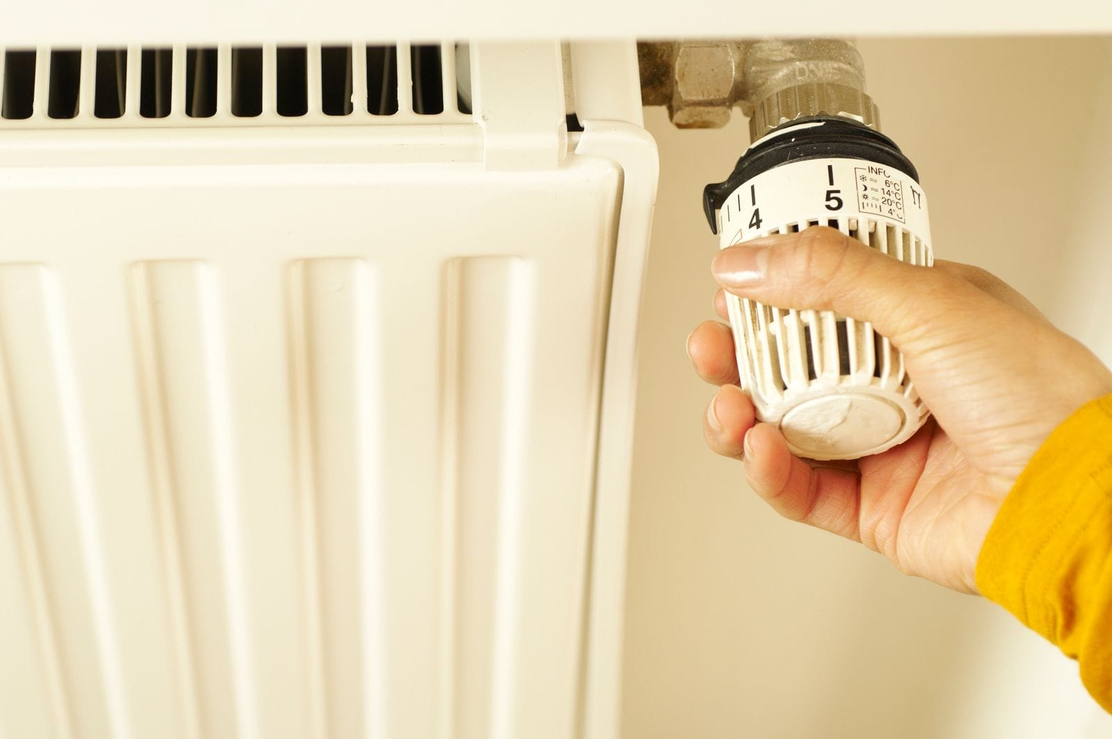 A hand setting a thermostatic radiator valve